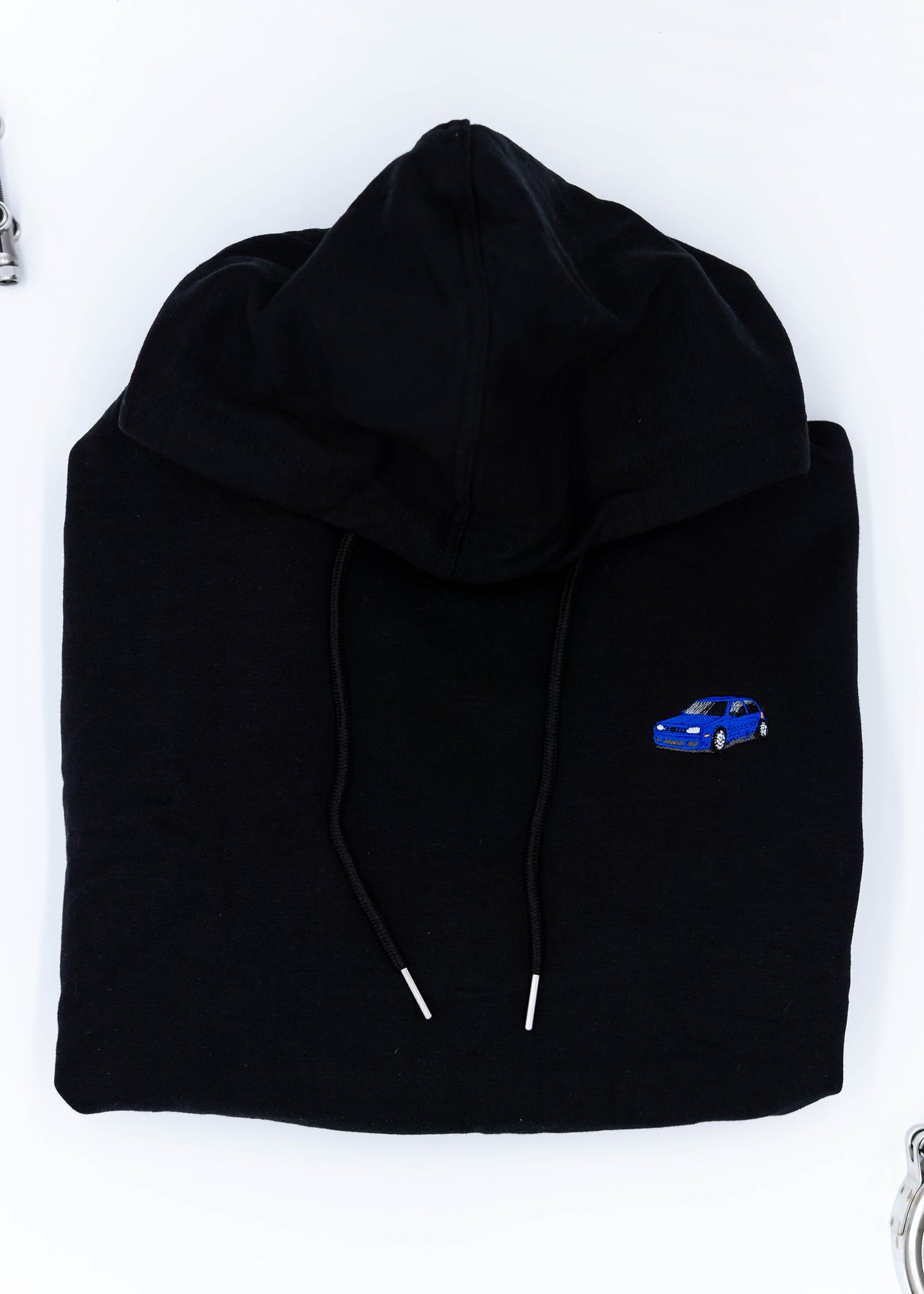 A black Mk4 Golf R32 cropped hoodie for women. Photo is a close up view of the cropped sweater with an embroidered blue Mk4 Golf R32. Fabric composition is cotton. The material is soft, stretchy, and non-transparent. The style of this crop hoodie is long sleeve, crewneck with a hood, hooded, with embroidery on the chest.