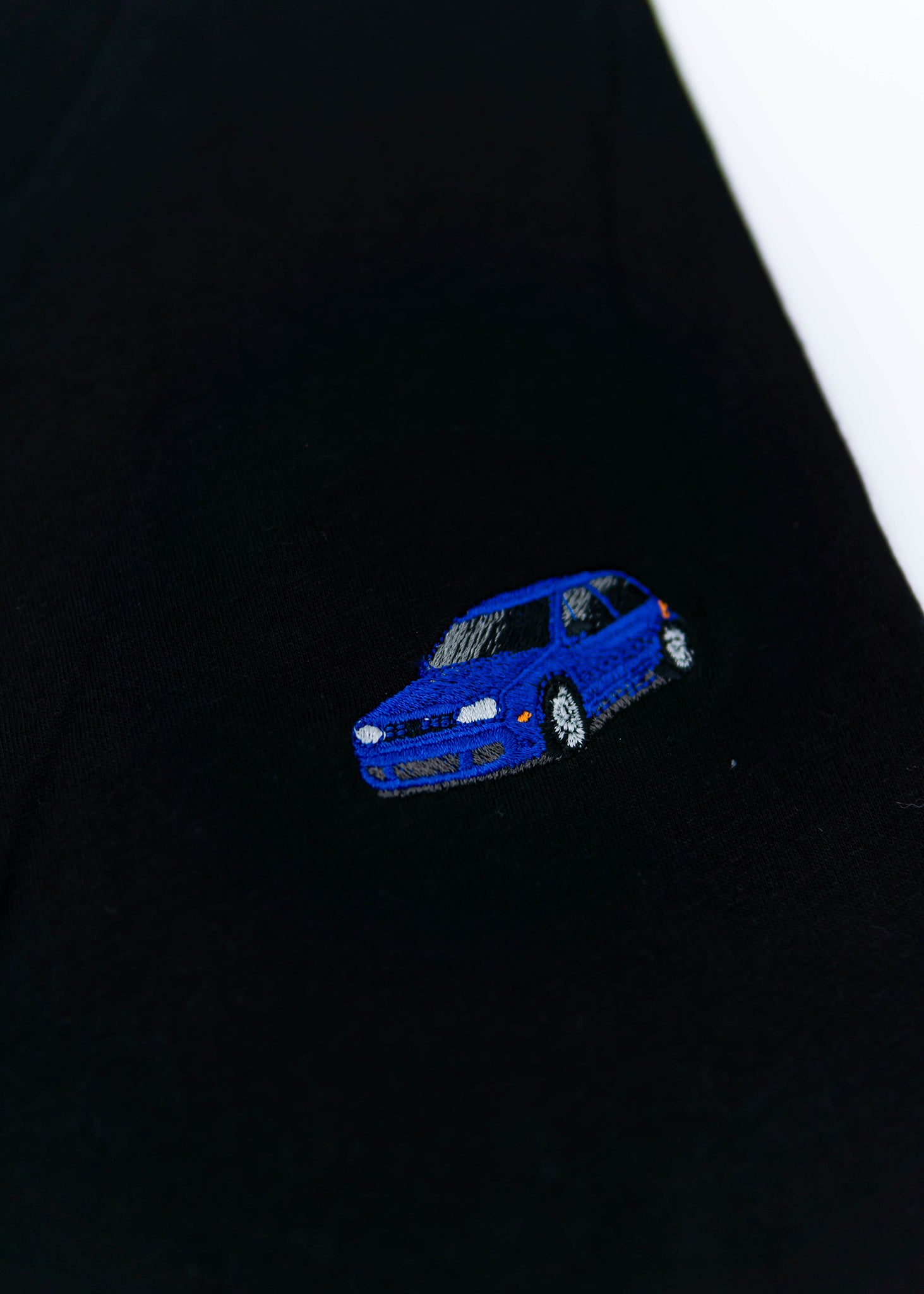 A black Mk4 Golf R32 T-Shirt for men. Photo is a close up view of the shirt with an embroidered blue Mk4 Golf R32. Fabric composition is 65% polyester, and 35% cotton. The material is very stretchy, soft, comfortable, breathable, and non-transparent. The style of this shirt is short sleeve, with a crewneck neckline.